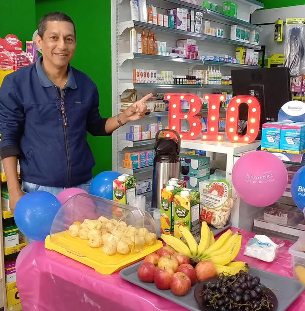 Atendimento no balcão da Drogaria Denis, com as prateleiras ao fundo